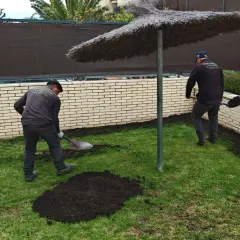 Jardineros esparciendo tierra, mostrando la diferencia entre sustrato y mantillo para mejorar el jardín.