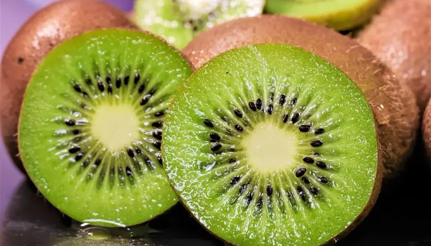Dos mitades de kiwi jugosas, con sus semillas negras y pulpa verde vibrante, listas para ser plantadas o disfrutadas.